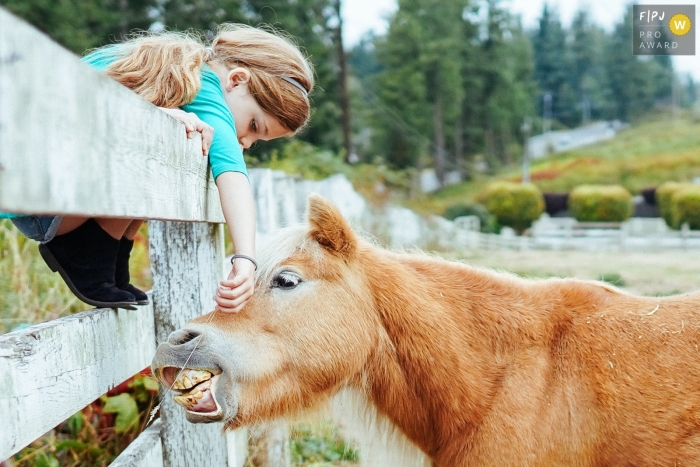 Photo by: <a href="https://www.fpja.com/documentary-family-photography-contests/ron-storer/seattle/2102763">Ron Storer - United States</a> Girl feeds a horse on a farm in Washington State. Seattle family photography.