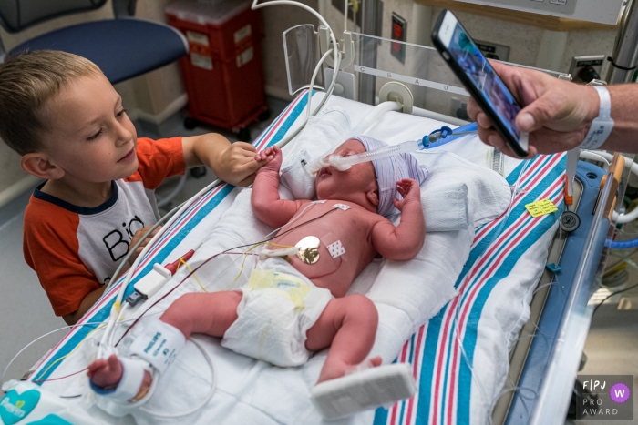 Photo by: <a href="https://www.fpja.com/documentary-family-photography-contests/anna-holden/connecticut/2103571">Anna Holden - United States</a> Connecticut Brothers meet for the first time, while mom, bedridden looks on via FaceTime at Hartford Hospital