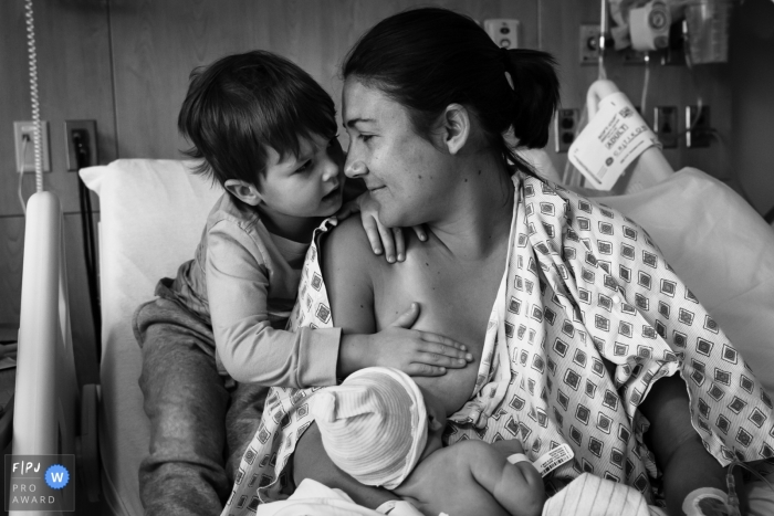 Photo by: <a href="https://www.fpja.com/documentary-family-photography-contests/loren-haar/ventura/2104146">Loren Haar - United States</a> California Mother breastfeeding while her older son tries to figure out how the milk comes out of there at Community Memorial Hospital