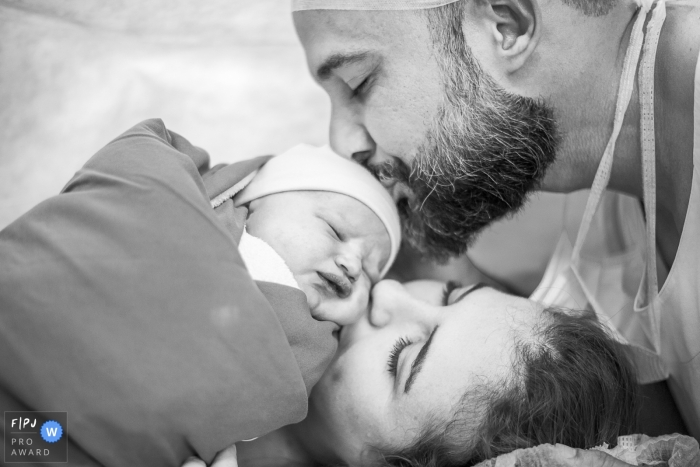 Photo by: <a href="https://www.fpja.com/documentary-family-photography-contests/claudia-ruiz/rio-de-janeiro/2104401">Claudia Ruiz - Brazil</a> Rio de Janeiro Brazil mom and dad kissing their new baby at Perinatal Barra