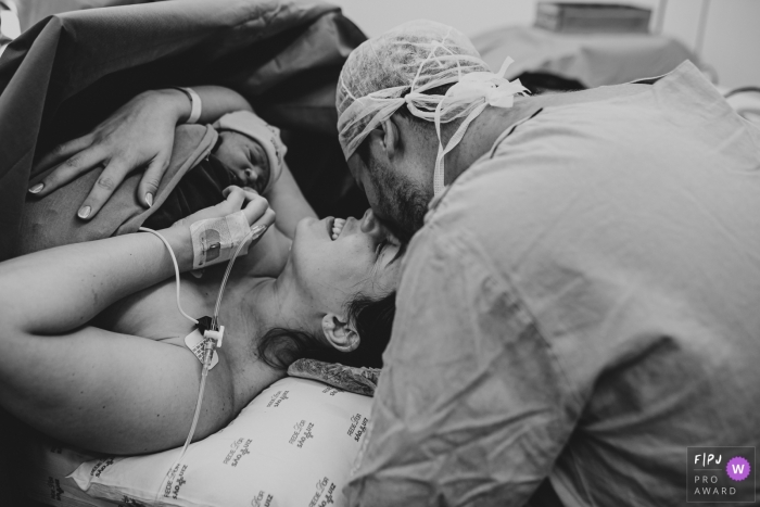 Photo by: <a href="https://www.fpja.com/documentary-family-photography-contests/ellen-brito/sao-paulo/2104527">Ellen Brito - Brazil</a> Sao Paulo Brazil mom and dad kiss after hospital delivery of their new baby - Now we are complete. Delivery at Hospital e Maternidade São Luiz
