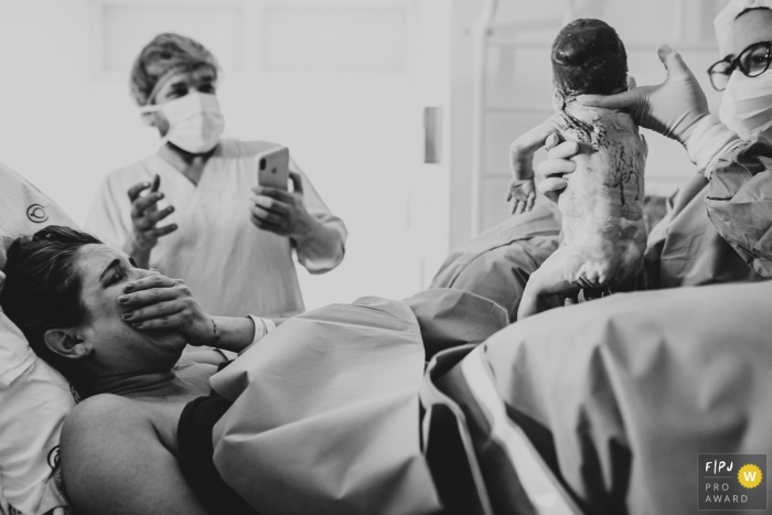 Photo by: <a href="https://www.fpja.com/documentary-family-photography-contests/ellen-brito/sao-paulo/2104531">Ellen Brito - Brazil</a> Maternidade Pro Matre doctor holds up the baby for mom to see for the first time
