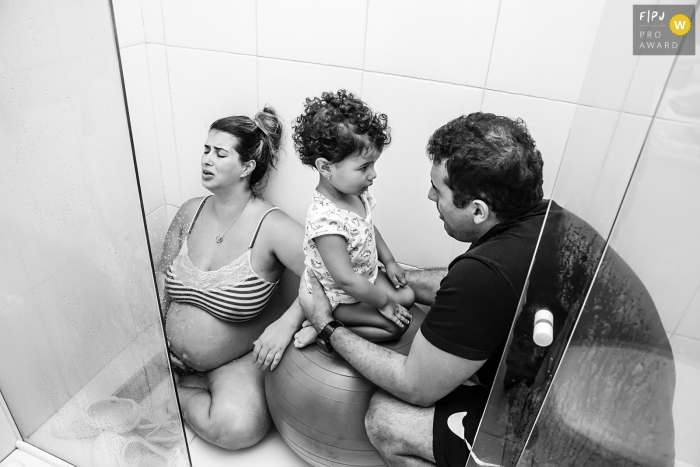 Photo by: <a href="https://www.fpja.com/documentary-family-photography-contests/gisele-soares/rio-de-janeiro/2104571">Gisele Soares - Brazil</a> Rio de Janeiro Brazil Pregnant woman in labor in the shower, accompanied by her husband and eldest daughter