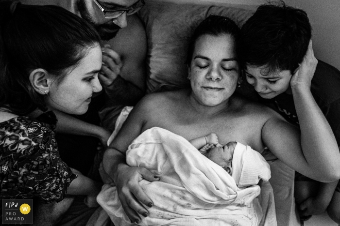 Sao Paulo mom holds her new baby with the old children cuddled around to check out their new sibling.