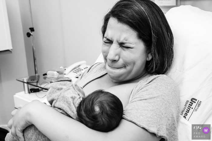 Hospital Unimed Nova Friburgo mother cringing as her baby is nursing.