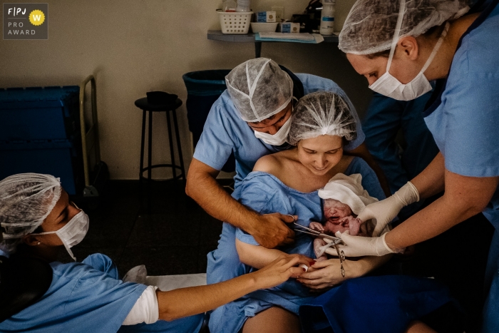 Photo by: <a href="https://www.fpja.com/documentary-family-photography-contests/thiago-braga/florianopolis/2104751">Thiago Braga - Brazil</a> Cutting the umbilical cord, baby being held by the mother, with support from the obstetrical nurse and medical team, with the father cutting the cord at Maternidade Santa Helena