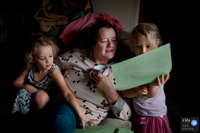 Photo by: <a href="http://fpja.com/documentary-family-photography-contests/william-bazlinton/dorset/2102875">William Bazlinton - United Kingdom</a> Dorset Family Photojournalism | Sisters showing their mother their drawings