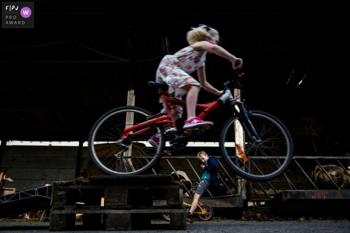 Photo by: <a href="https://www.fpja.com/documentary-family-photography-contests/sven-soetens/east-flanders/2103015">Sven Soetens - Belgium</a> Flanders, Belgium outdoor shoot of children riding bikes and going off a jump.