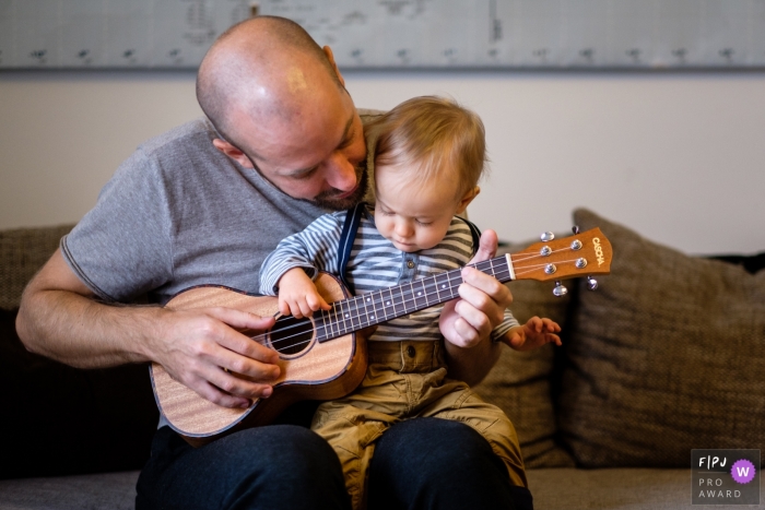 Photo by: <a href="https://www.fpja.com/documentary-family-photography-contests/jess-haverkamp/berlin/2103383">Jess Haverkamp - Germany</a> Berlin Germany child Enthralled with dad and the guitar