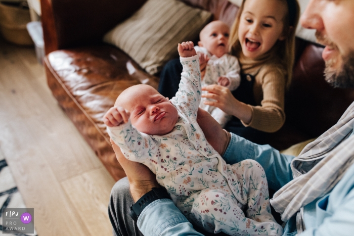 Picture of a London England Baby twin stretching at home with dad and big sister London England Baby twin stretching at home with dad and big sister