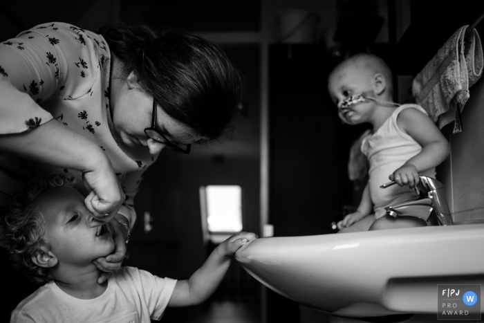 Photo by: <a href="https://www.fpja.com/documentary-family-photography-contests/mitzy-geluk/zeeland/2103513">Mitzy Geluk - Netherlands</a> Zeeland Netherlands mom helping child - Brush those teeth