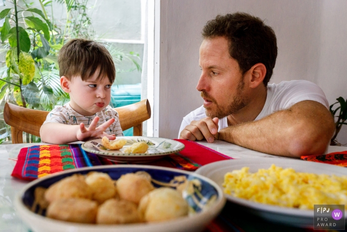 Photo by: <a href="https://www.fpja.com/documentary-family-photography-contests/priscilla-mondo/sao-paulo/2103736">Priscilla Mondo - Brazil</a> Sao Paulo Brazil boy and dad eating at the table - Don't touch my bread