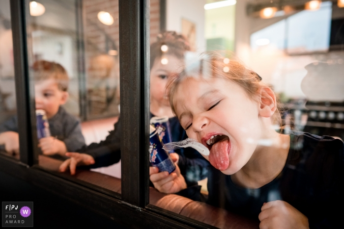 Photo by: <a href="https://www.fpja.com/documentary-family-photography-contests/sybil-rondeau/nantes/2103960">Sybil Rondeau - France</a> Nantes Loire-Atlantique kids eating ice cream at the window pane
