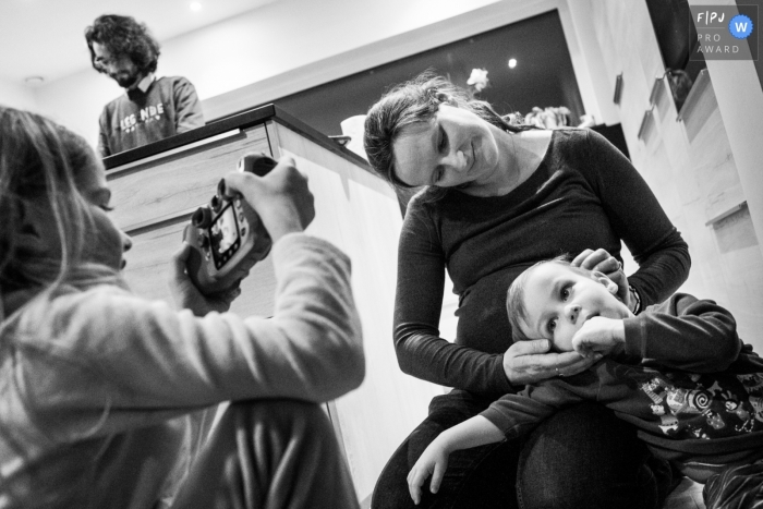 Photo by: <a href="https://www.fpja.com/documentary-family-photography-contests/joshua-dhondt/antwerpen/2103989">Joshua Dhondt - Belgium</a> Flanders family in the kitchen, older sister taking a picture of younger sibling.