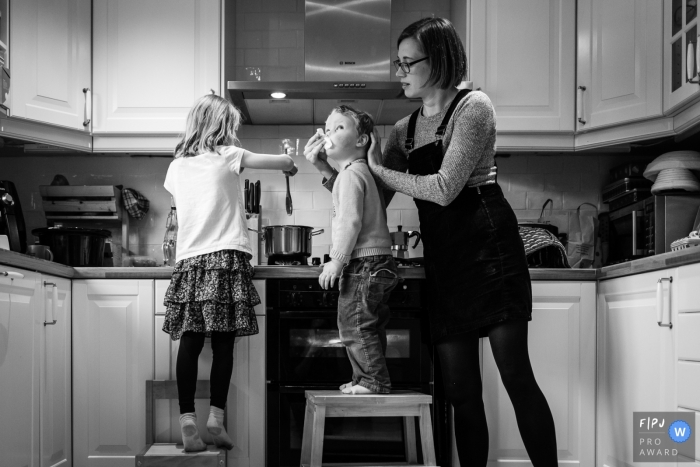 Cambridgeshire England Mum wipes boy's nose while he cooks with sister