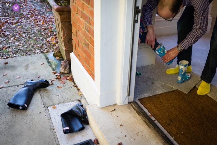 Photo by: <a href="https://www.fpja.com/documentary-family-photography-contests/alice-chapman/cambridgeshire/2104046">Alice Chapman - United Kingdom</a> Cambridgeshire England Dad removes boy's wellies / rain boots