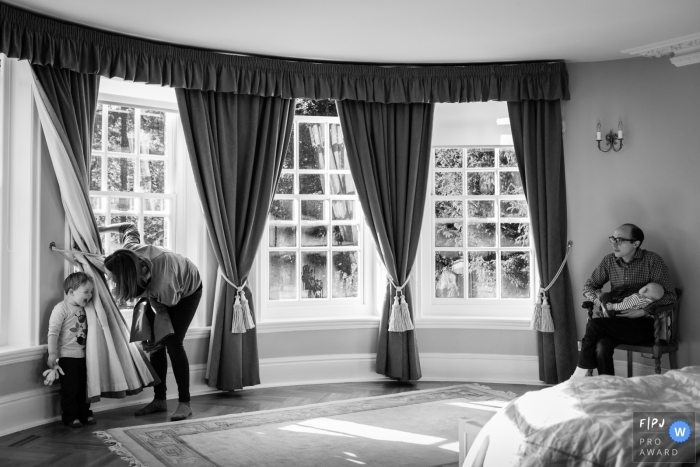 Photo by: <a href="https://www.fpja.com/documentary-family-photography-contests/alice-chapman/cambridgeshire/2104053">Alice Chapman - United Kingdom</a> Cambridgeshire England Mum and boy play hide and seek while dad holds baby