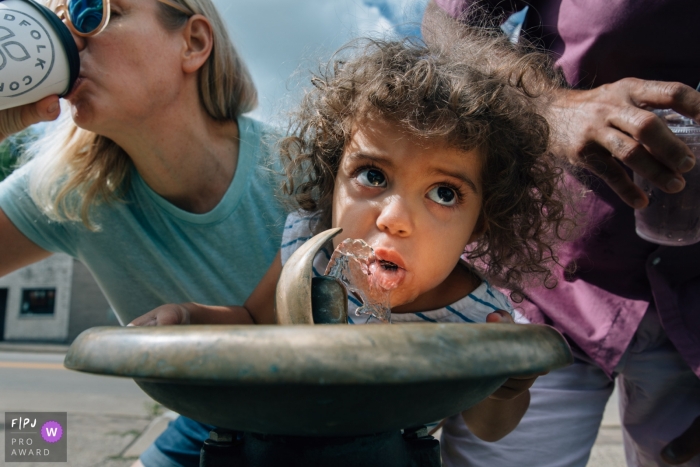 Madison Wisconsin Girl drinks from a "bubbler" while Mom & Dad hold her up and drink coffee