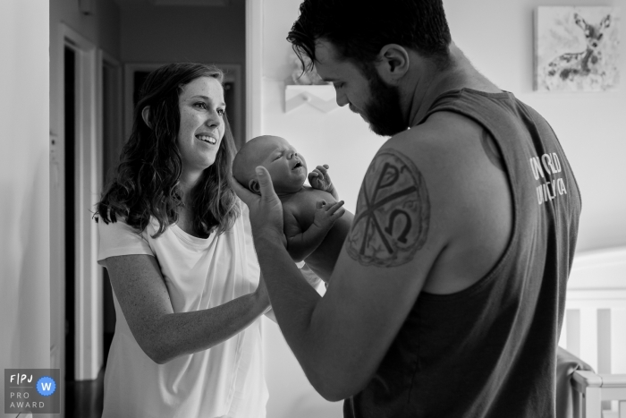 Photo by: <a href="https://www.fpja.com/documentary-family-photography-contests/loren-haar/ventura/2104169">Loren Haar - United States</a> Ventura California mom Passing off the new baby to dad at home