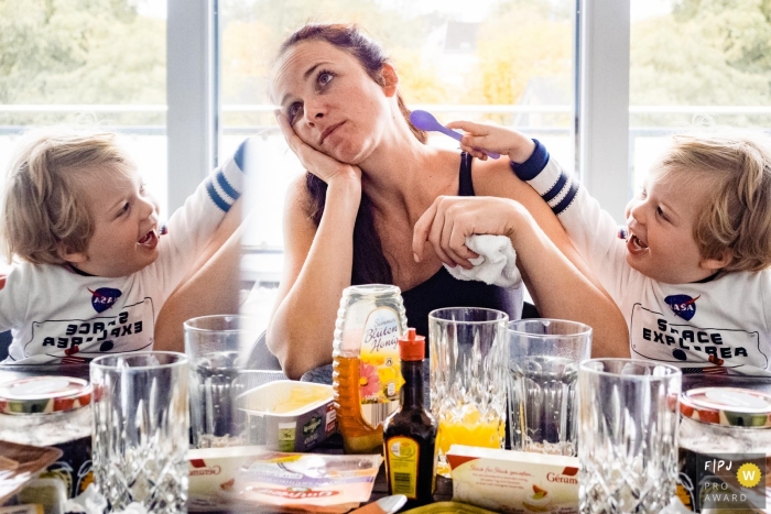Photo by: <a href="https://www.fpja.com/documentary-family-photography-contests/katrin-k%C3%BCllenberg/dusseldorf/2104190">Katrin Küllenberg - Germany</a> Dusseldorf North Rhine-Westphalia Mom's patience is double with work in this reflected image