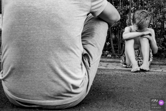 Dusseldorf father sits with his son who is distaught over something.