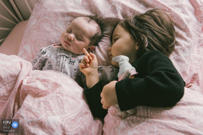 Photo by: <a href="https://www.fpja.com/documentary-family-photography-contests/adeline-leonti/montreal/2104233">Adeline Leonti - Canada</a> Quebec family moment of a little girl touching her little sister's cheek