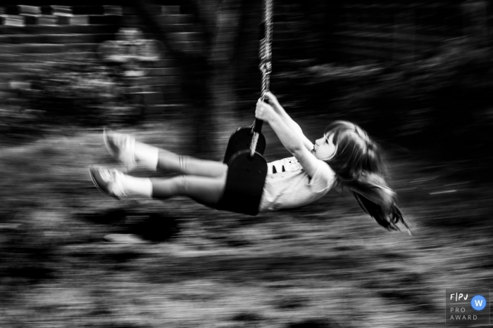 Photo by: <a href="https://www.fpja.com/documentary-family-photography-contests/linda-mauch/kent/2104305">Linda Mauch - United Kingdom</a> Kent England Little girl plays on swing - slow shutter pan photo