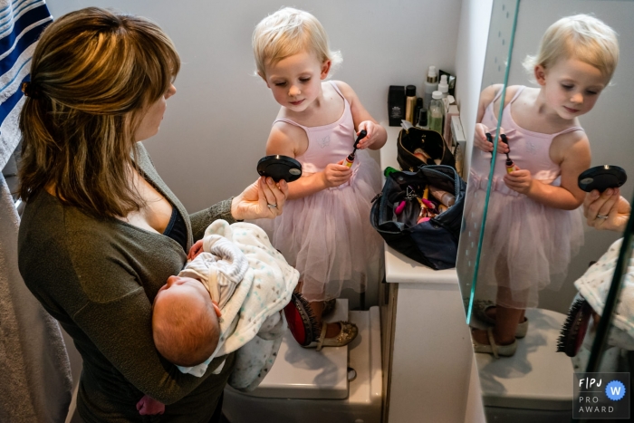 Image showing a Kent England Mother holding a hand mirror for daughter as she opens up the lip gloss Kent England Mother holds a hand mirror for daughter as she opens up the lip gloss