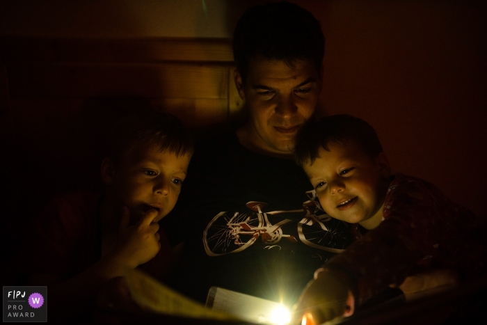 Photo by: <a href="https://www.fpja.com/documentary-family-photography-contests/melinda-guerini-temesi/budapest/2104352">Melinda Guerini Temesi - Hungary</a> Budapest Hungary family evening tale reading time with flashlights