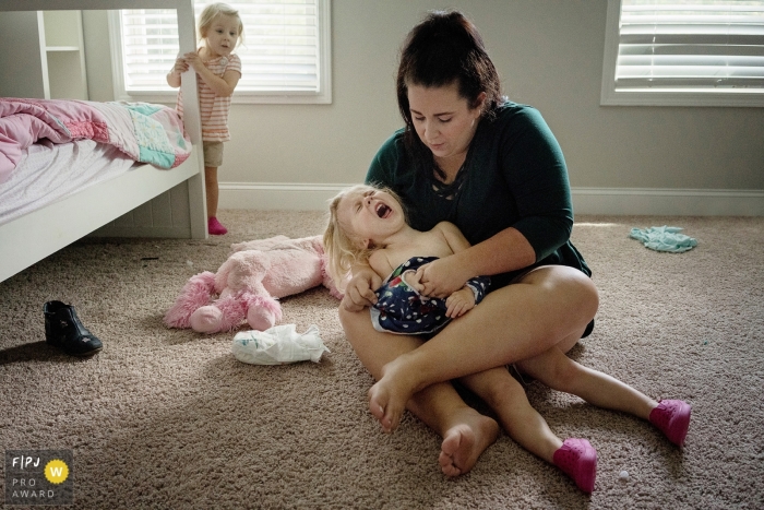 Photo by: <a href="https://www.fpja.com/documentary-family-photography-contests/julie-ambos/key-west/2104719">Julie Ambos - United States</a> Key West Florida mom struggles to dress one of her young daughters