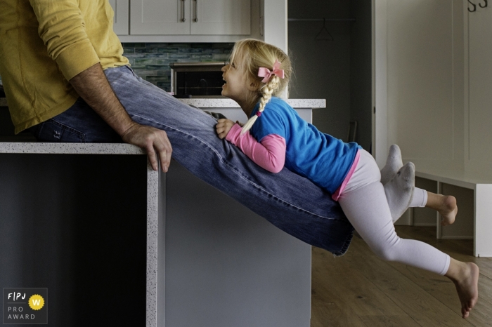 Photo by: <a href="https://www.fpja.com/documentary-family-photography-contests/julie-ambos/key-west/2104729">Julie Ambos - United States</a> Key West Florida Leg Lifts with a young girl in the family kitchen