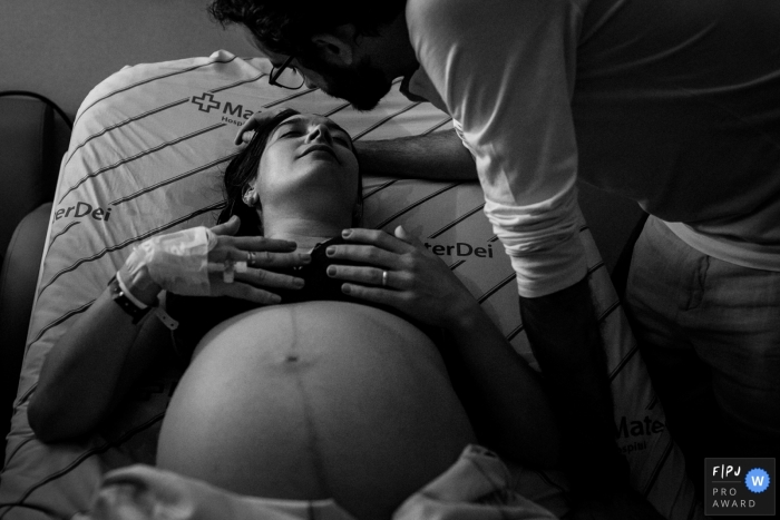 Photo by: <a href="https://www.fpja.com/documentary-family-photography-contests/adriana-costa/belo-horizonte/2105413">Adriana Costa - Brazil</a> Minas Gerais birthing photo showing a moment of affection between the couple during labor
