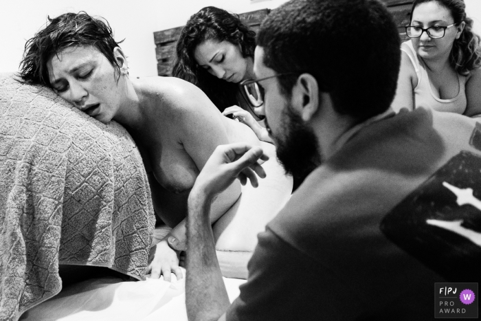 A woman going through labor is exhausted, and is surrounded by her family | Sao Paulo Birth Photography