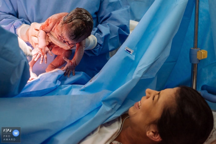 Photo by: <a href="https://www.fpja.com/documentary-family-photography-contests/claudia-ruiz/rio-de-janeiro/2106101">Claudia Ruiz - Brazil</a> Mom looks at her newborn with excitement as the doctor reveals the precious face | Rio de Janeiro Birth Photo