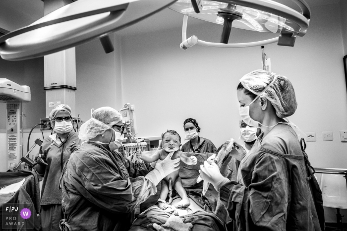 Operating room at Maternidade de Campinas image as baby is lifted up out of his mother in Sao Paulo