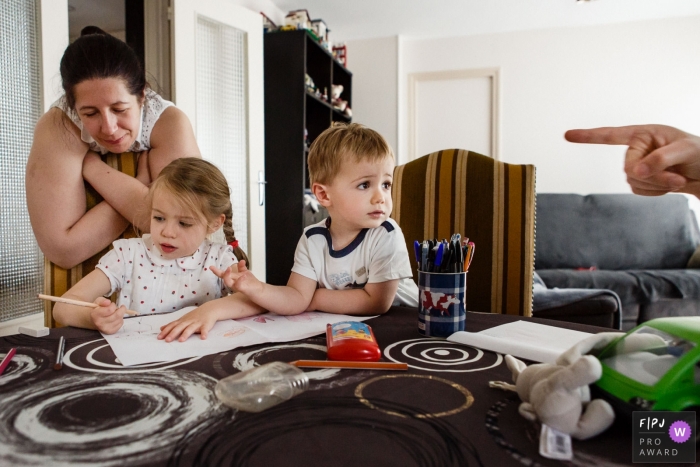 Photo by: <a href="https://www.fpja.com/documentary-family-photography-contests/annie-gozard/paris/2105022">Annie Gozard - France</a> Paris family photojournalism image of the hand at the table with the kids at home.