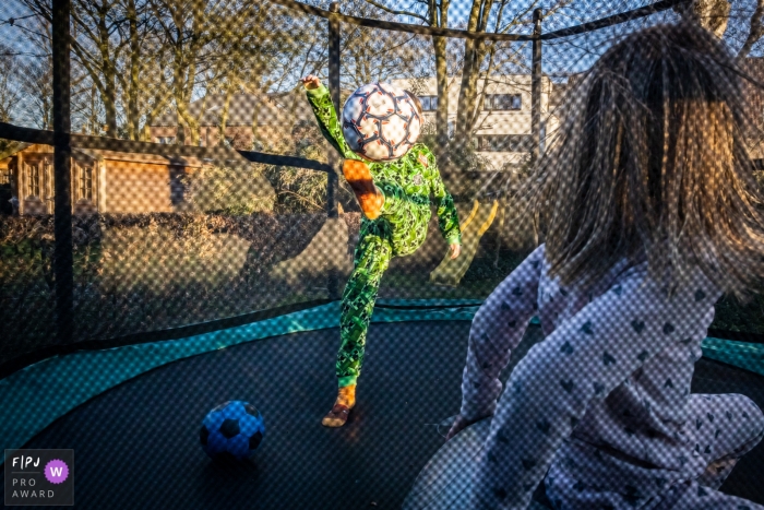 Photo by: <a href="https://www.fpja.com/documentary-family-photography-contests/sven-rammeloo/east-flanders/2105101">Sven Rammeloo - Belgium</a> Kids play in a trampoline with a ball during a family photoshoot in East Flanders