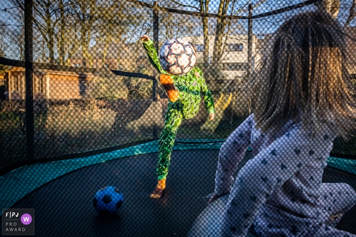 Les enfants jouent dans un trampoline avec un ballon lors d'une séance photo en famille en Flandre orientale