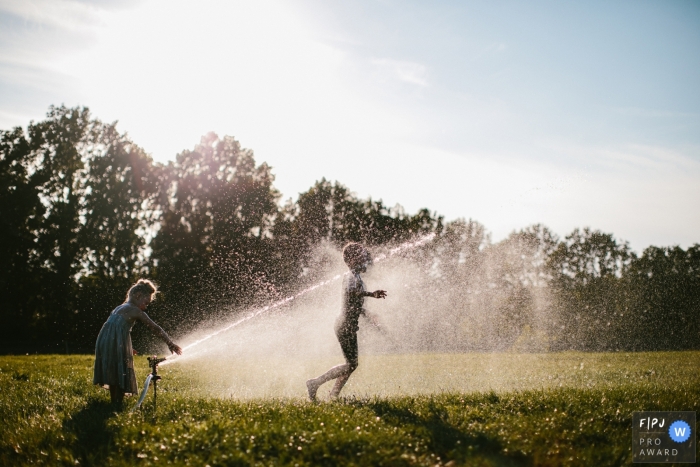 Photo by: <a href="https://www.fpja.com/documentary-family-photography-contests/jolanda-boer/drenthe/2105311">Jolanda Boer - Netherlands</a> Netherlands Family Photography | A couple of children enjoy the first warm days of the year by running through thet sprinklers