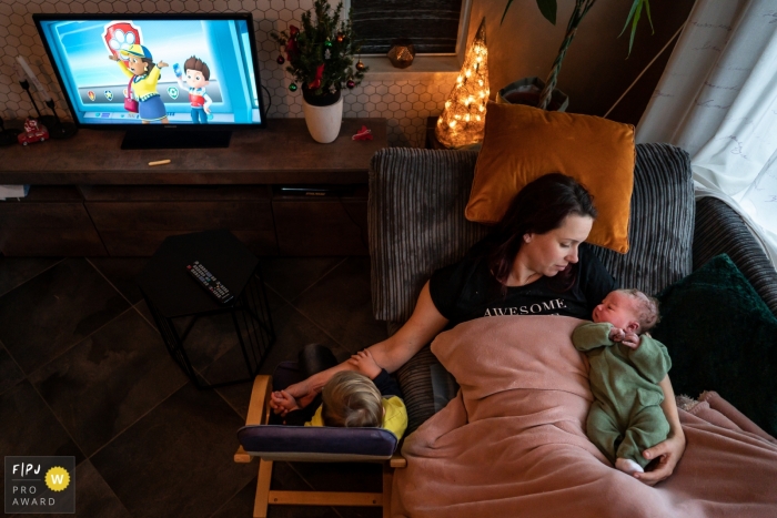 Photo by: <a href="https://www.fpja.com/documentary-family-photography-contests/louise-van-den-broek/flevoland/2105358">Louise van den Broek - Netherlands</a> Mom relaxing with her newborn (couple hours old) and oldest son | Flevoland homebirth photography