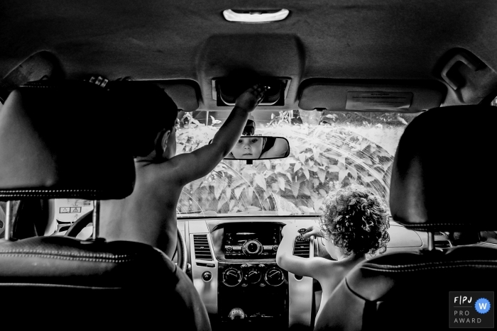 Two young men playing in the front seats of the auto having a good ole time playing | Minas Gerais documentary family photographer