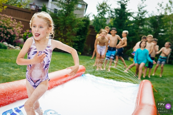 Washington family and kid photography | girl runs down a water slide as others are waiting for their turn