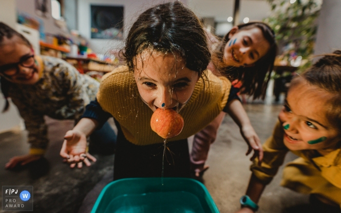 France children's birthday party photography of a girl playing a bobbing for apples game.