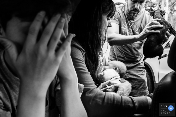 Un chien passe dans une voiture tandis qu'une mère tient son bébé | Séance photo de famille du dimanche au Brésil