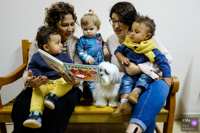 Family sit on a bench reading a book during a Sao Paulo family photo session