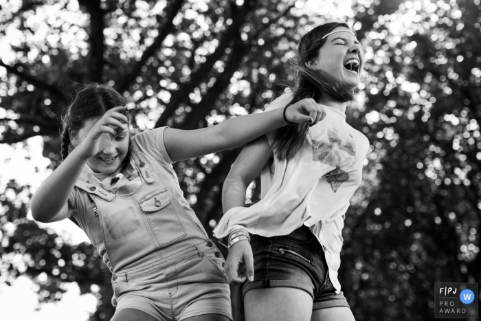 Photo by: <a href="https://www.fpja.com/documentary-family-photography-contests/joshua-dhondt/antwerpen/2106240">Joshua Dhondt - Belgium</a> Two girls having fun bumping hips and laughing | Belgium Family Photographer