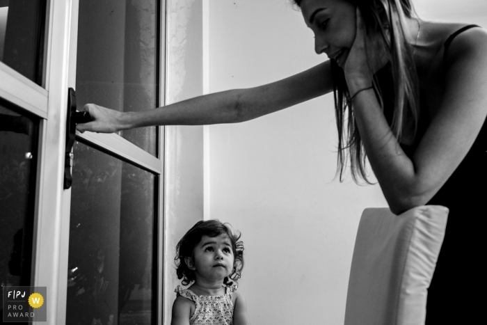 Le photographe de famille du Mato Grosso capture une mère fermant une porte vers l'extérieur pendant qu'une jeune fille regarde.