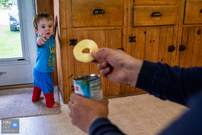CT Family photo of a dad enticing his toddler son to walk with a pineapple slice CT Family photo of a dad enticing his toddler son to walk with a pineapple slice.