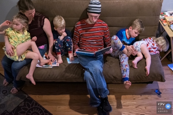 Connecticut family sitting on a sofa as papa lit un livre.