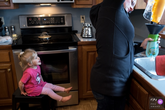Photo by: <a href="https://www.fpja.com/documentary-family-photography-contests/anna-holden/connecticut/2106609">Anna Holden - United States</a> A young girl lickin' her chops while 'helping' mom in the kitchen.